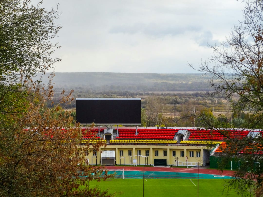 A big scoreboard screen above the grandstand of a community stadium