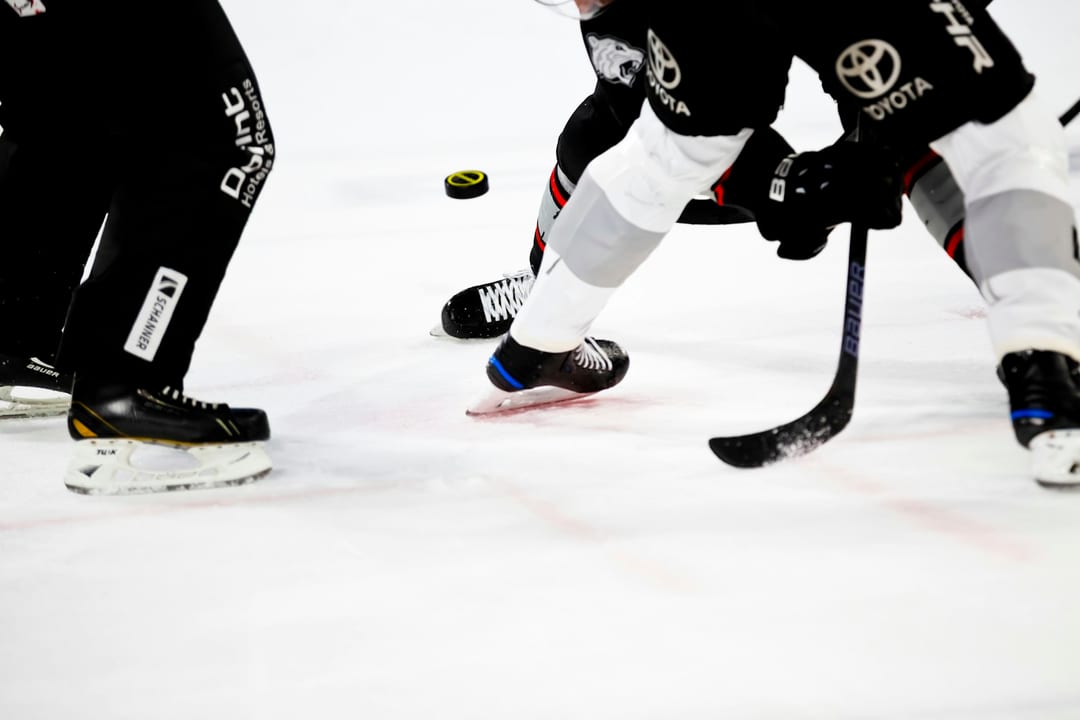 Hockey players skating for the puck at a face-off